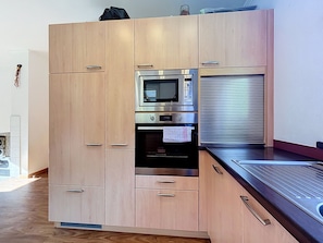 A modern kitchen with wooden cabinets, a built-in oven, and a stainless steel microwave. - Ferienhaus Siegele by Interhome (See)