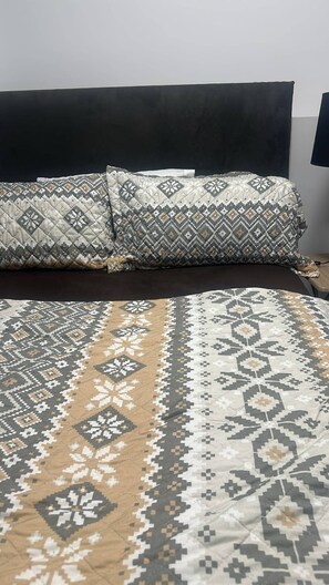 Ein Bett mit einem gemusterten Überwurf und einem Kissen mit geometrischem Design.