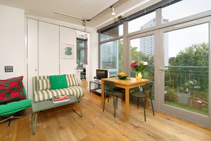 Ein modernes Wohnzimmer mit einer Couch, einem Glastisch, einem Esstisch mit Stühlen und einem Fernseher.