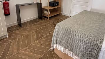 Une chambre à coucher avec un lit, une armoire en bois, une petite table avec un vase et un extincteur.