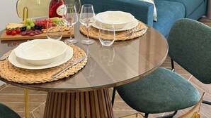 Een eettafel gedekt met borden, glazen en een fles wijn, met een blauwe bank op de achtergrond.