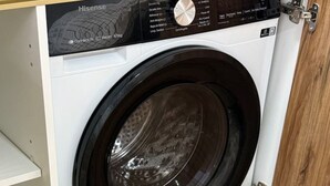 Een voorlader wasmachine in een keukenkast met een houten vloer.