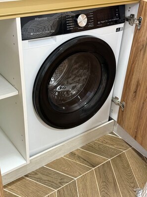 Eine Frontlader-Waschmaschine in einem Küchenschrank mit Holzboden.