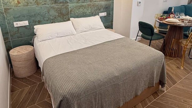 Een moderne slaapkamer met een groot bed, een rond nachtkastje en een zithoek met een tafel en stoelen.
