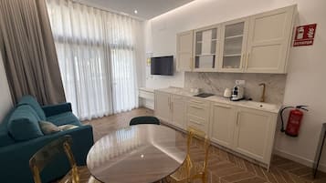Un salon moderne comprenant un canapé, une table à manger et des chaises. On y trouve également un coin cuisine avec des placards et un extincteur.