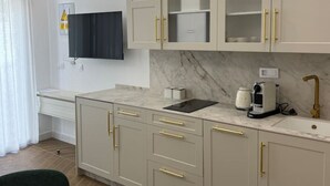 Een moderne keuken met marmeren aanrecht, een ingebouwde oven en een koffieapparaat.
