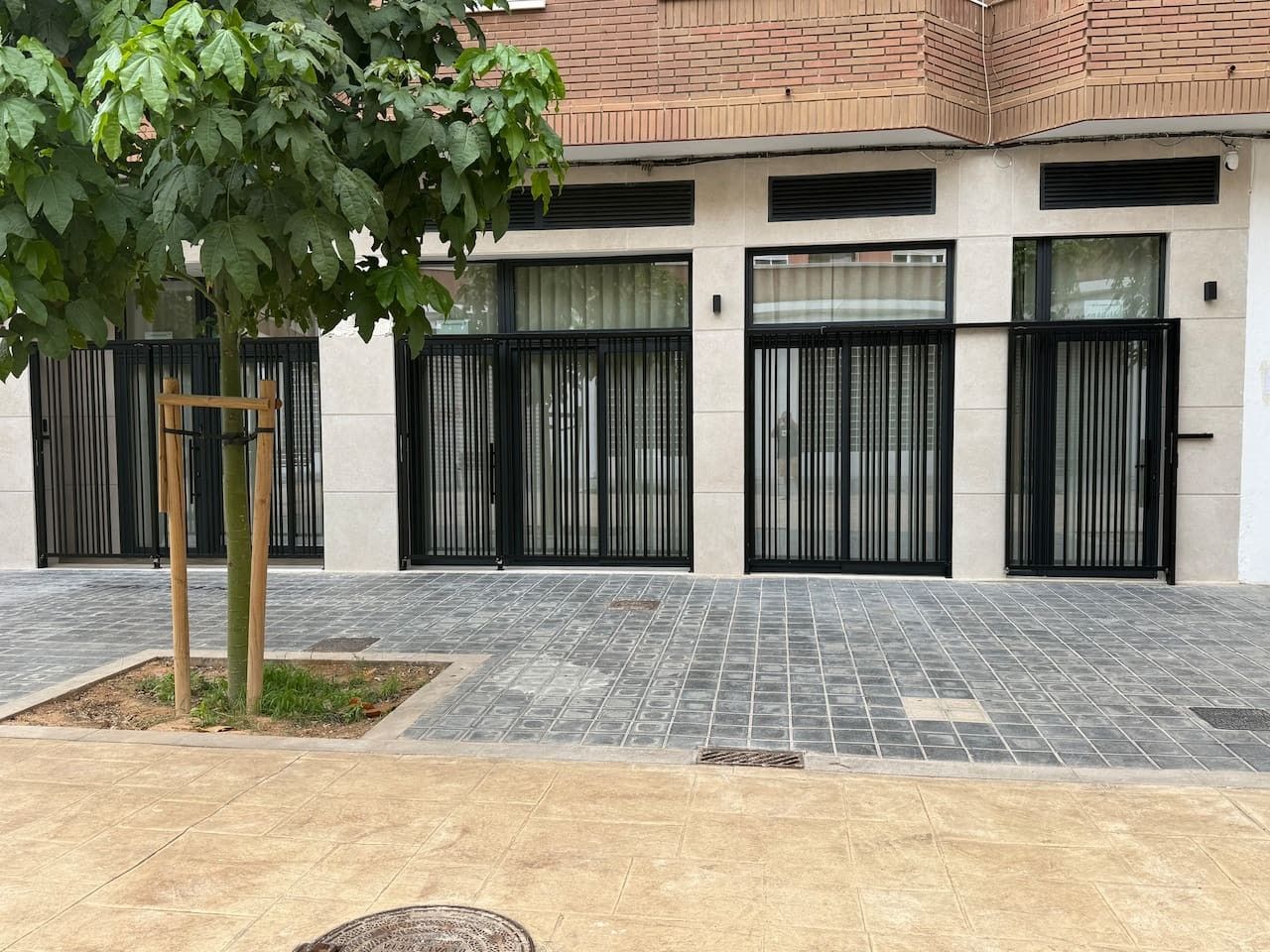Un bâtiment au design moderne, avec un rez-de-chaussée carrelé et un étage supérieur en briques.