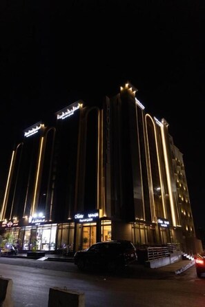 A multi-story hotel with illuminated signage and a modern architectural design. - Akarim Al Waha Serviced Apartments (jeddah)