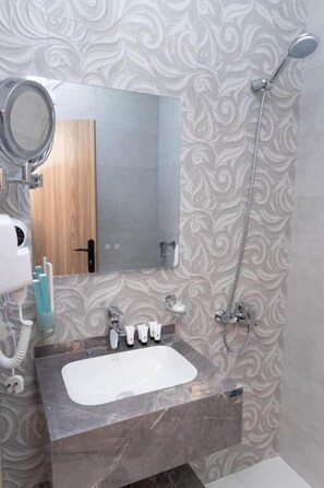 A bathroom with a marble sink, a mirror, a handheld showerhead, and toiletries. - Akarim Al Waha Serviced Apartments (jeddah)