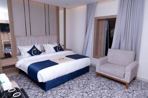 A hotel room with a bed, a sofa, a TV, and a desk with a phone. - Akarim Al Waha Serviced Apartments (jeddah)