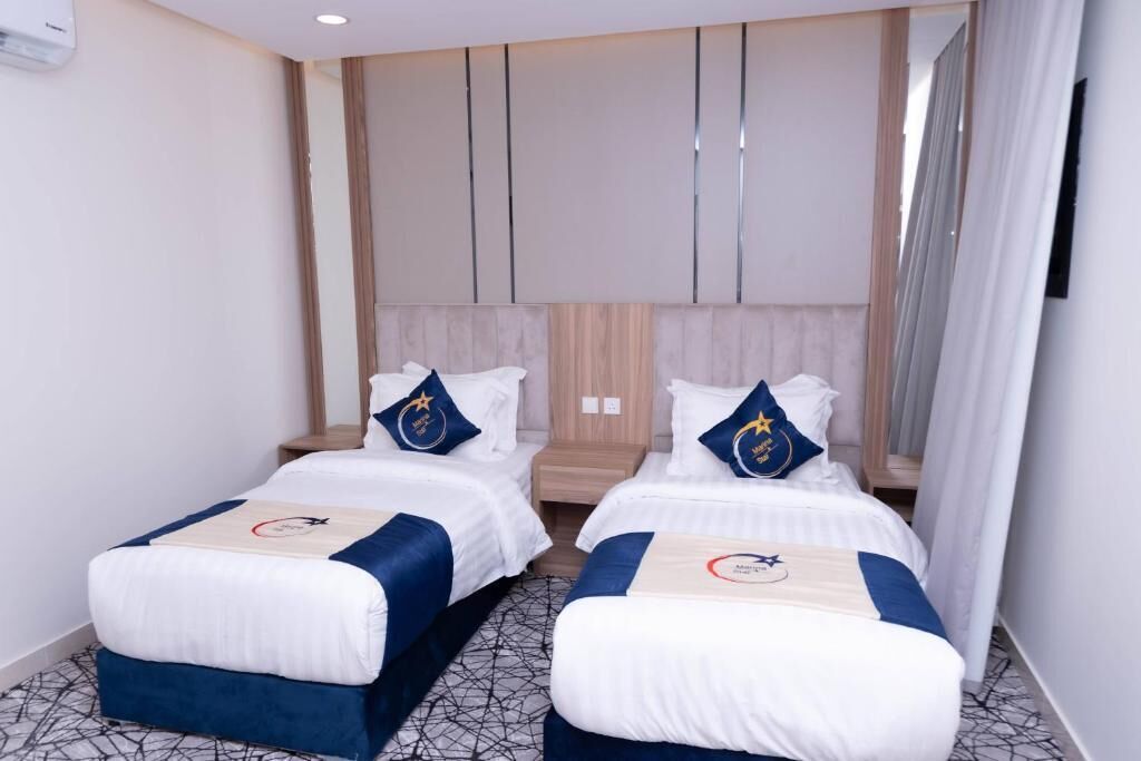 Una habitación de hotel con dos camas, cada una con una colcha azul y almohadas a juego.
