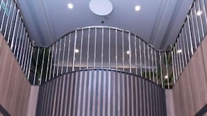 Un moderno vestíbulo de hotel con un ascensor central, una barandilla curva e iluminación empotrada en el techo.