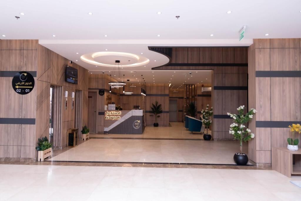A hotel reception area with a reception desk, a clock, and a sign indicating the direction to the parking area.