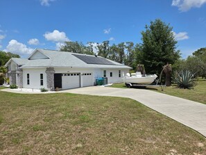 A single-story house with a garage, a boat in the driveway, and a well-maintained lawn. -  4-br 3-ba Beautiful Suncoast Pool House centrally located in Lecanto Fl. (Lecanto)