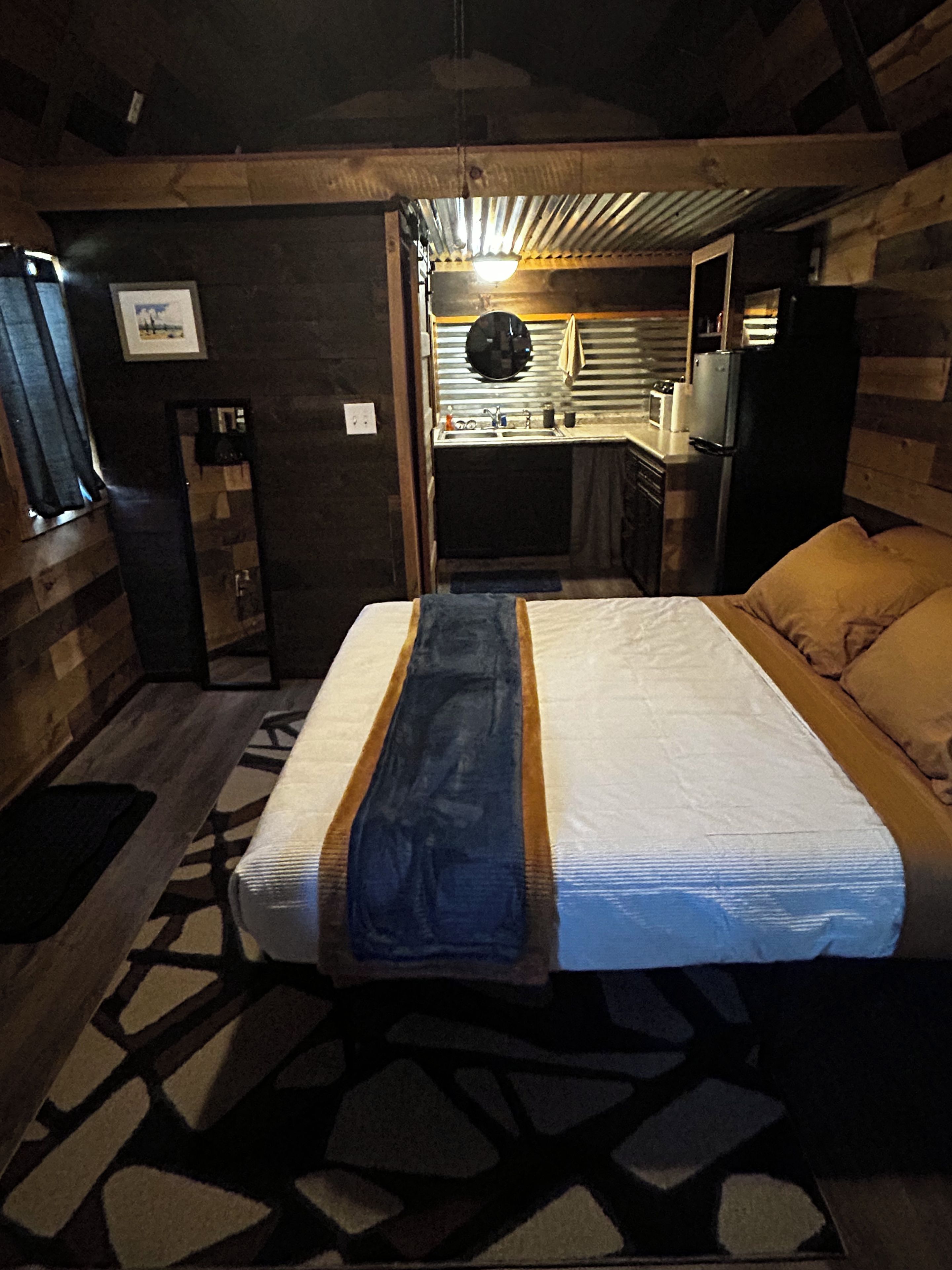 A compact room with a bed, a small kitchenette, and a window.