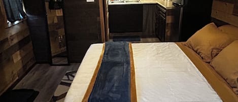 Una habitación funcional con cama, kitchenette pequeña y ventana.