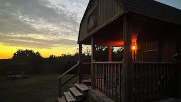 Uma cabana de madeira com varanda e degraus que levam até ela.