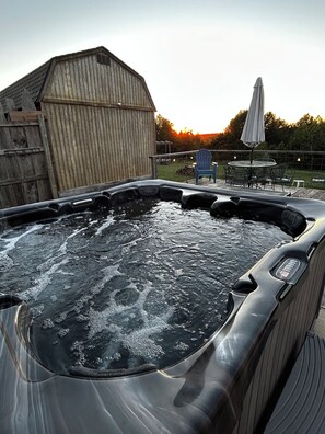 Un jacuzzi con terraza de madera, un cobertizo de madera y un patio con mobiliario exterior.