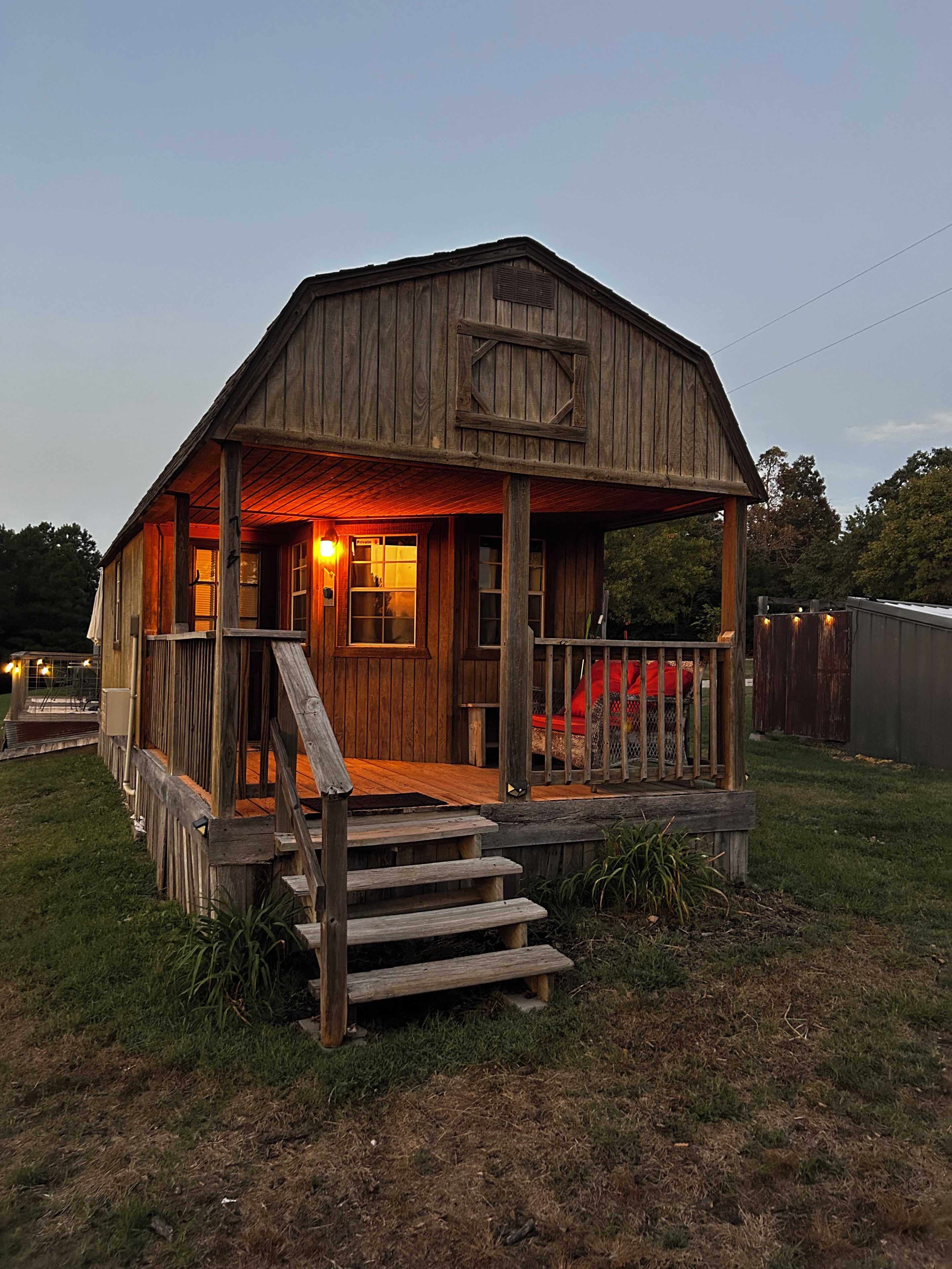 A wooden cabin with a porch and steps leading to the entrance.