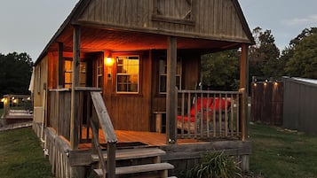 A wooden cabin with a porch and steps leading to the entrance.
