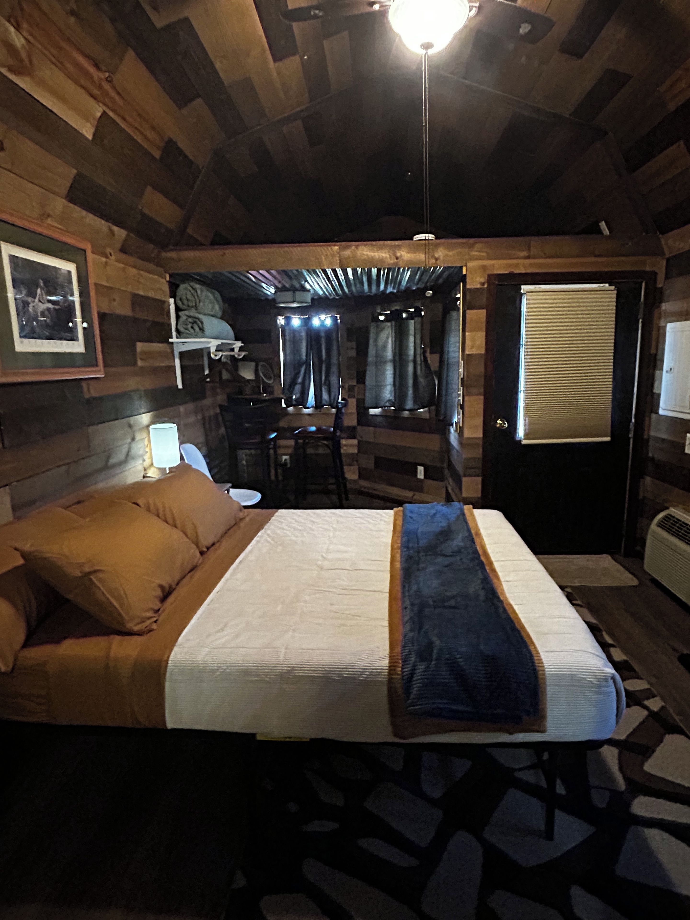 A wooden cabin-style bedroom with a bed, a desk, and a chair.