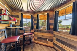 A room with wooden panel walls, a table, two chairs, and a hanging coat rack.