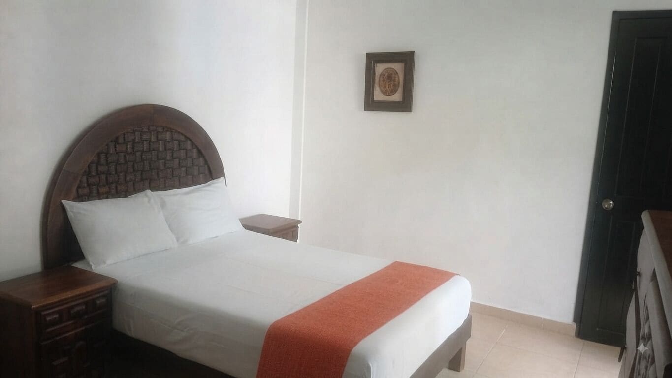 A single bed with a headboard, a bedside table, and a framed picture on the wall.