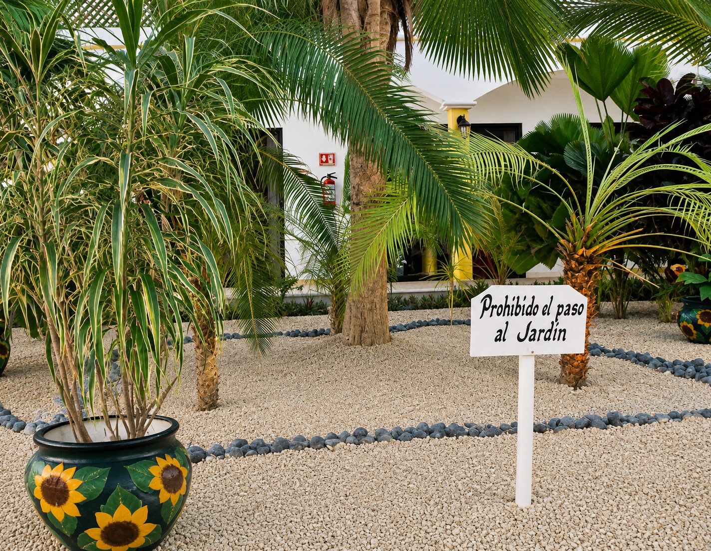 A garden area with a sign that reads 'Prohibido el paso al Jardín' indicating no entry to the garden.