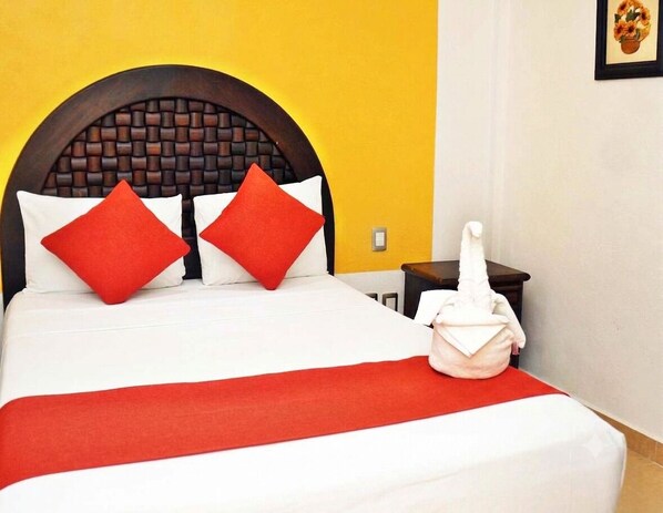 A bed with a wooden headboard, red and white pillows, and a red bedspread.