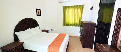 Un dormitorio con cama, mesitas de noche, armario y puerta.