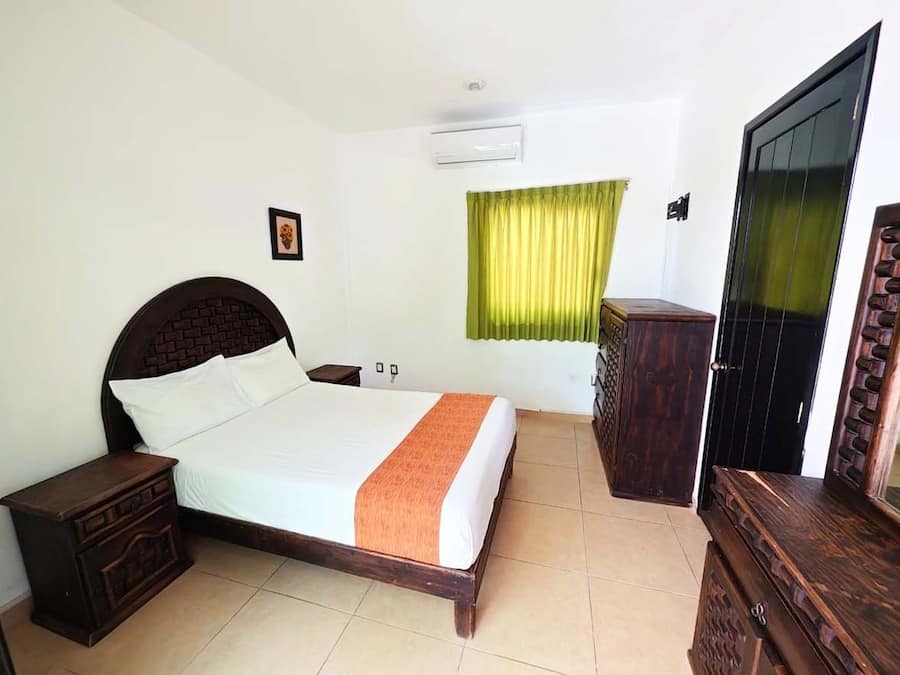 Un dormitorio con cama, mesitas de noche, armario y puerta.