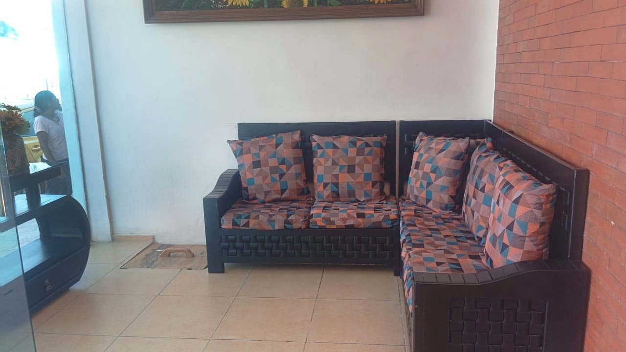 A corner seating area with a sofa and a small table, a tiled floor, and a brick wall.