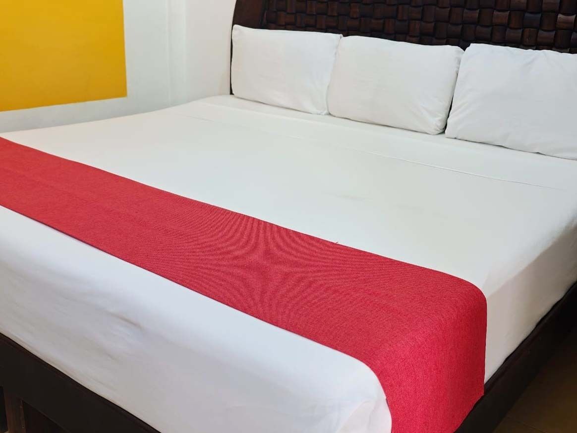 Un lit avec du linge de lit blanc et une couverture rouge.