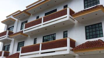 Un hotel de varios pisos con balcones, una señal que indica que es un hotel y una entrada amplia con puertas de cristal.