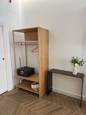 Ein Zimmer mit einem Holzschrank, einem schwarzen Konsolentisch und einer Vase mit Blumen.