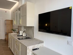 Une cuisine moderne dotée d’un plan de travail en marbre, d’appareils électroménagers intégrés et d’un grand téléviseur à écran plat fixé au mur.