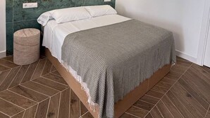 Ein modernes Schlafzimmer mit einem Bett, einem Kopfteil mit Wandleuchten und einem Fischgrätenparkettboden.