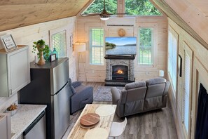 Ein gemütliches Blockhaus-Interieur mit Kamin, Sitzgruppe und Küche.