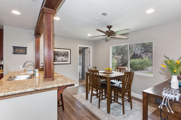 A kitchen with a granite countertop, wooden chairs, a dining table, and a ceiling fan. - The River's Edge - Private Home with River Access, Spa, and Karaoke (Three Rivers)
