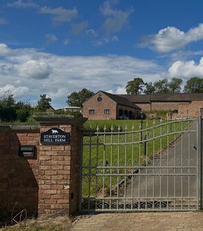 Una entrada tancada amb reixa metàl·lica a Staverton Hill Farm, amb un mur de maó.