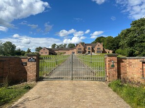 Una entrada tancada a Staverton Hill Farm, amb un mur de maó i una porta metàl·lica.