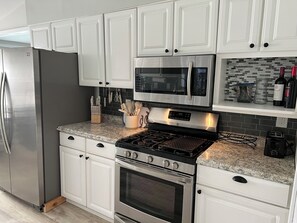 A kitchen with white cabinets, stainless steel appliances, and a granite countertop. - Cozy 2-bedroom cottage - St Clair River access in beautiful Algonac with AC (Algonac)