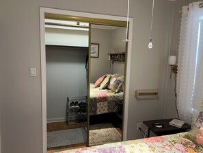 A bedroom with a bed, a bedside table, a nightstand, a mirror, a wardrobe, and a shoe rack. - Cozy 2-bedroom cottage - St Clair River access in beautiful Algonac with AC (Algonac)