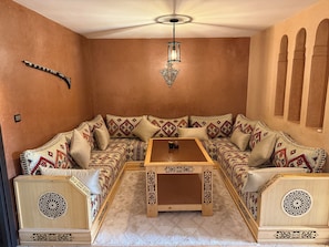 A cozy room with a patterned sofa, a wooden coffee table, and a decorative light fixture.