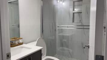 Une salle de bain moderne équipée de toilettes, d’une douche et d’un meuble-lavabo avec un miroir.
