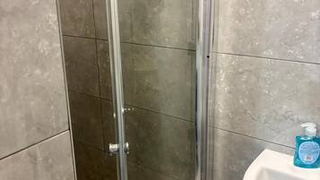 Ein Badezimmer mit Glasduschtür, Waschbecken und einer Handseifenflasche.
