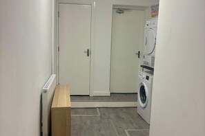 Un cuarto de lavandería con lavadora y secadora, un banco de madera y una puerta.