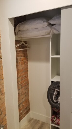 A closet with a brick wall, white shelves, and hanging space. - Comfy 1 Bedroom Apartment! Salt Lake City. Close to UofU (Salt Lake City)