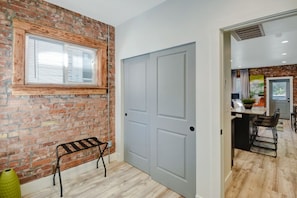 A hallway with a brick wall, a grey door, and a bench. - Comfy 1 Bedroom Apartment! Salt Lake City. Close to UofU (Salt Lake City)