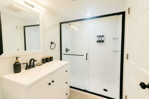 A bathroom with a white vanity, black faucet, and a glass shower enclosure.